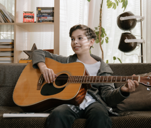 kid playing the guitar on the couch