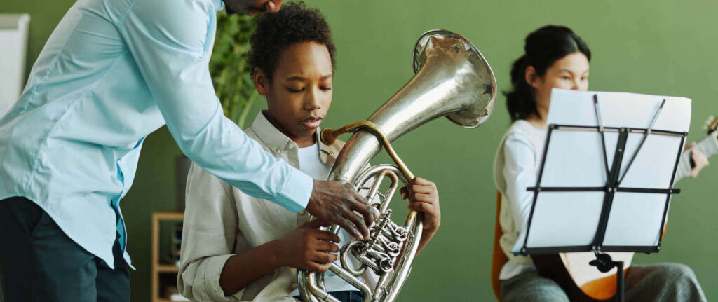 Student learning to play the French horn at the music lesson