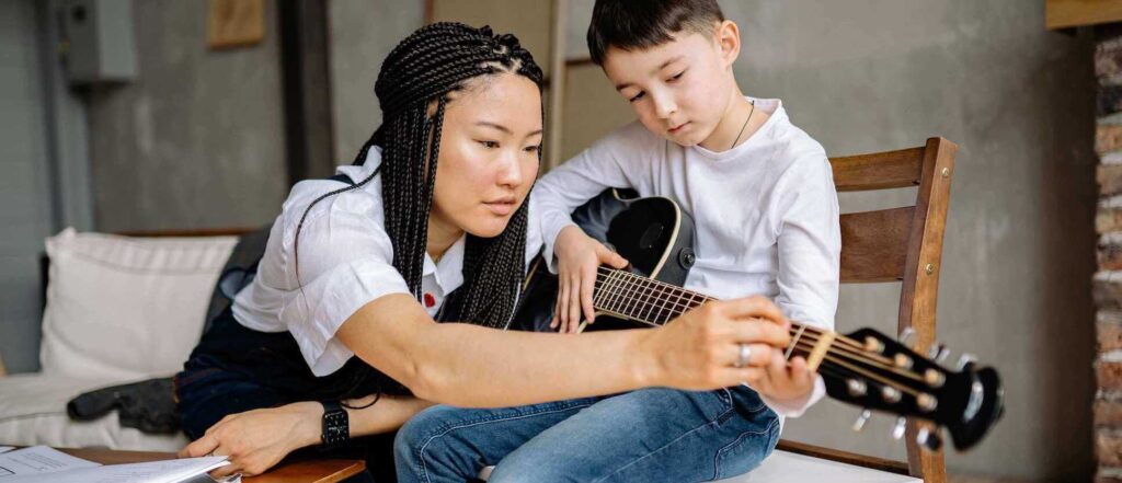 guitar teacher showing the student how to play the guitar