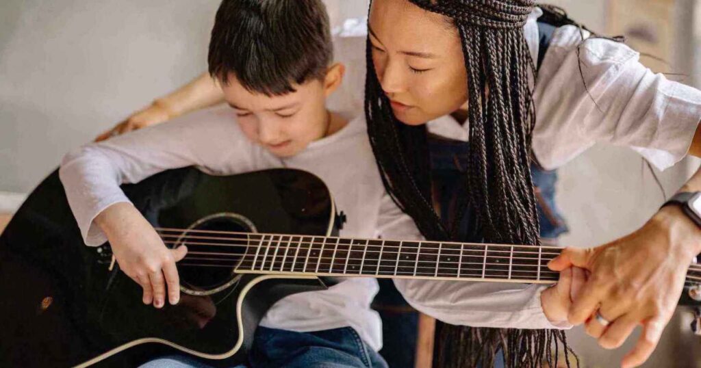 guitar teacher showing the student how to play the guitar