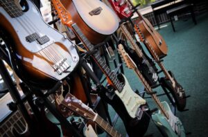 a mix of different guitars hanging on a wall