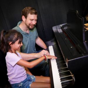 piano teacher and student sitting at the piano playing during a lesson