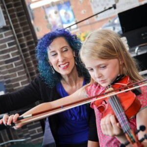 violin instructor and student playing together while the instructor shows the student proper technique