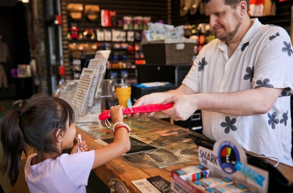 a staff member handing a young student a recorder flute at the front desk