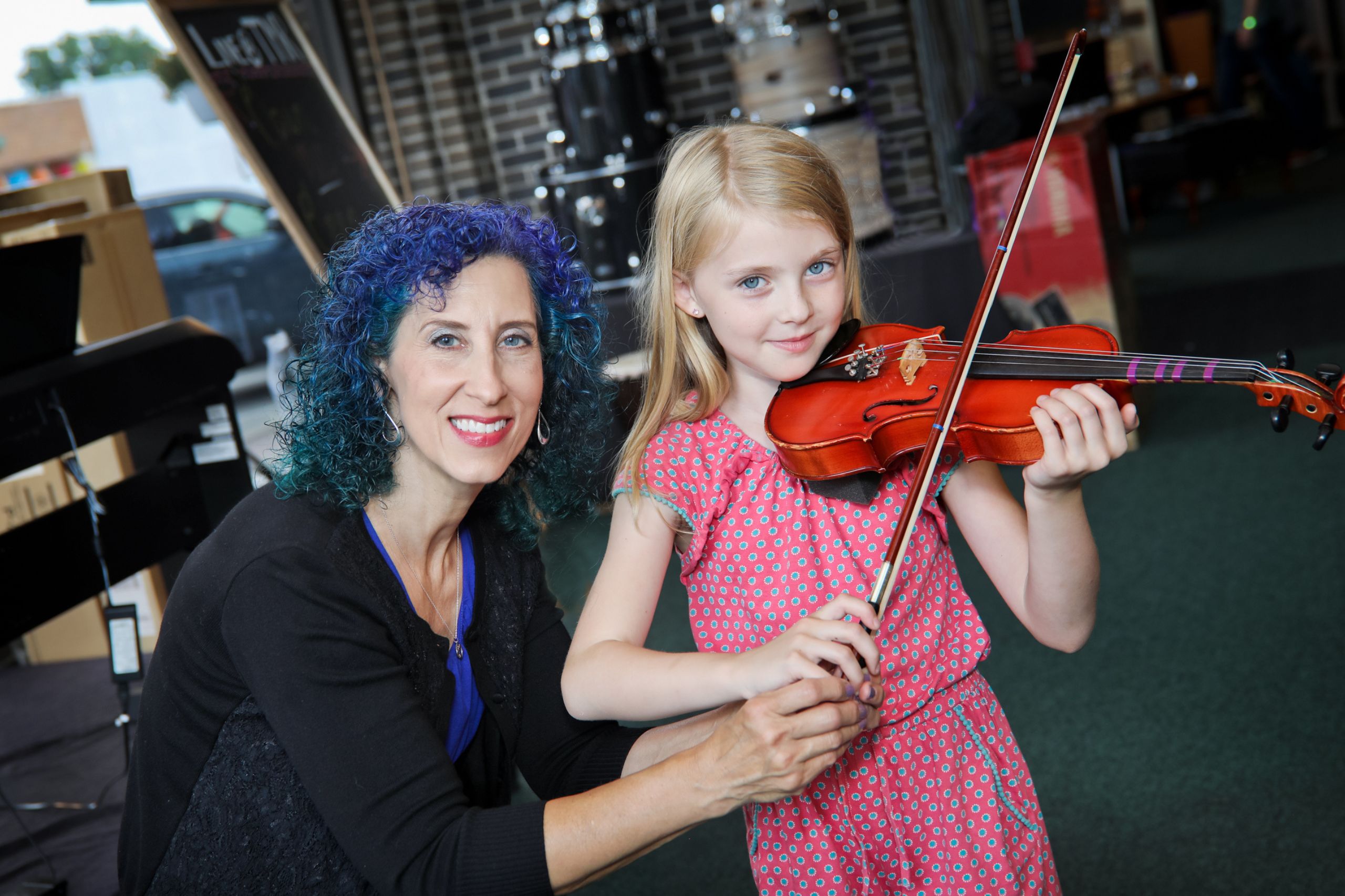 student holding a violin standing with her teacher and both of them are smiling