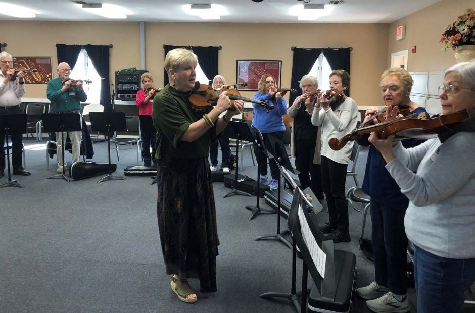 one of our instructors working with a group of seniors playing the violin