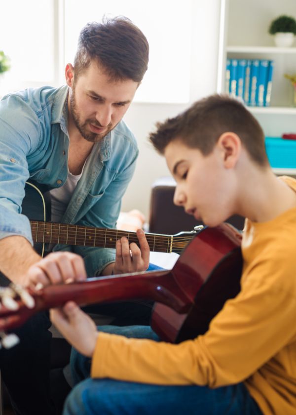 guitar teacher teaching the kid play the guitar at home Orland Park IL