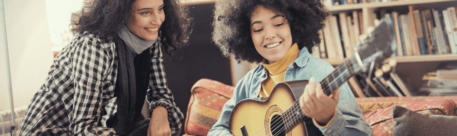 student learning to play the guitar with a teacher