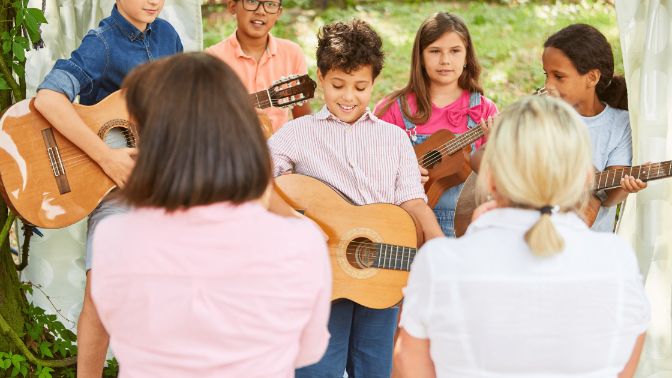kids in a summer music camp performing a concert with their guitars
