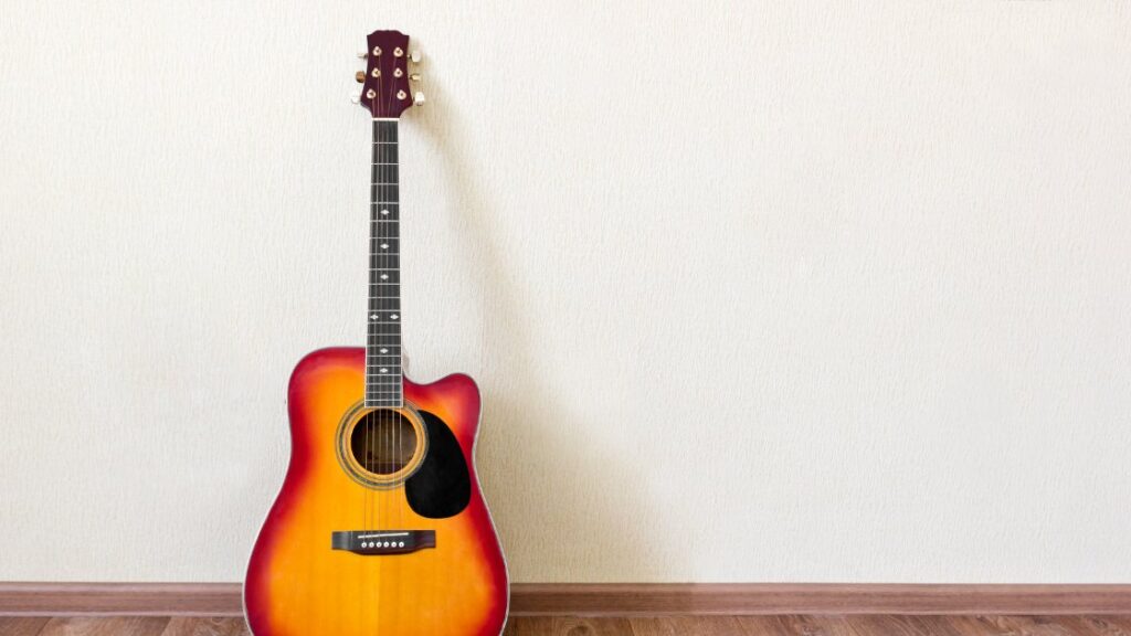 acoustic guitar sitting on wall