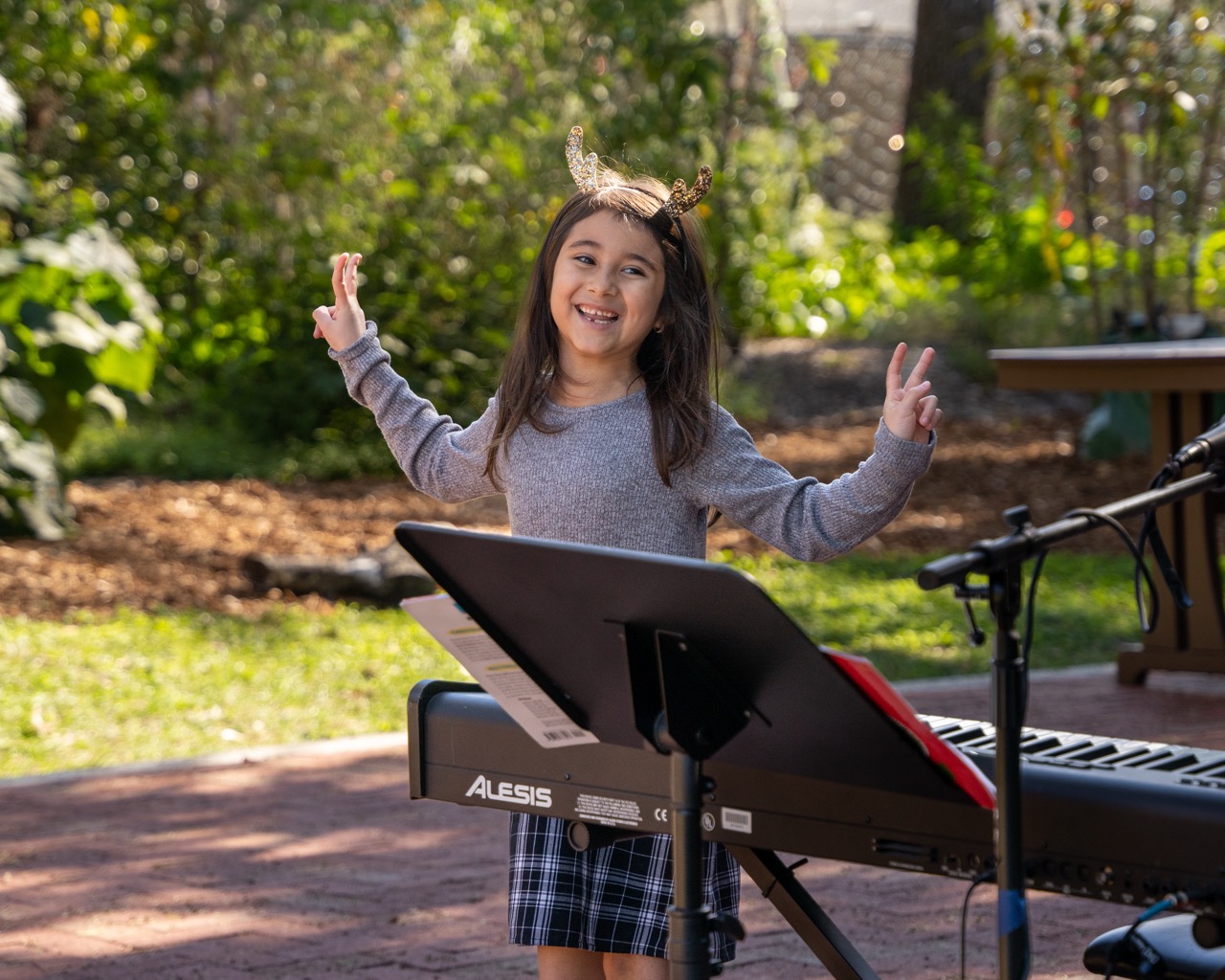 young student walking away from a piano holding up peace signs after a recital performance