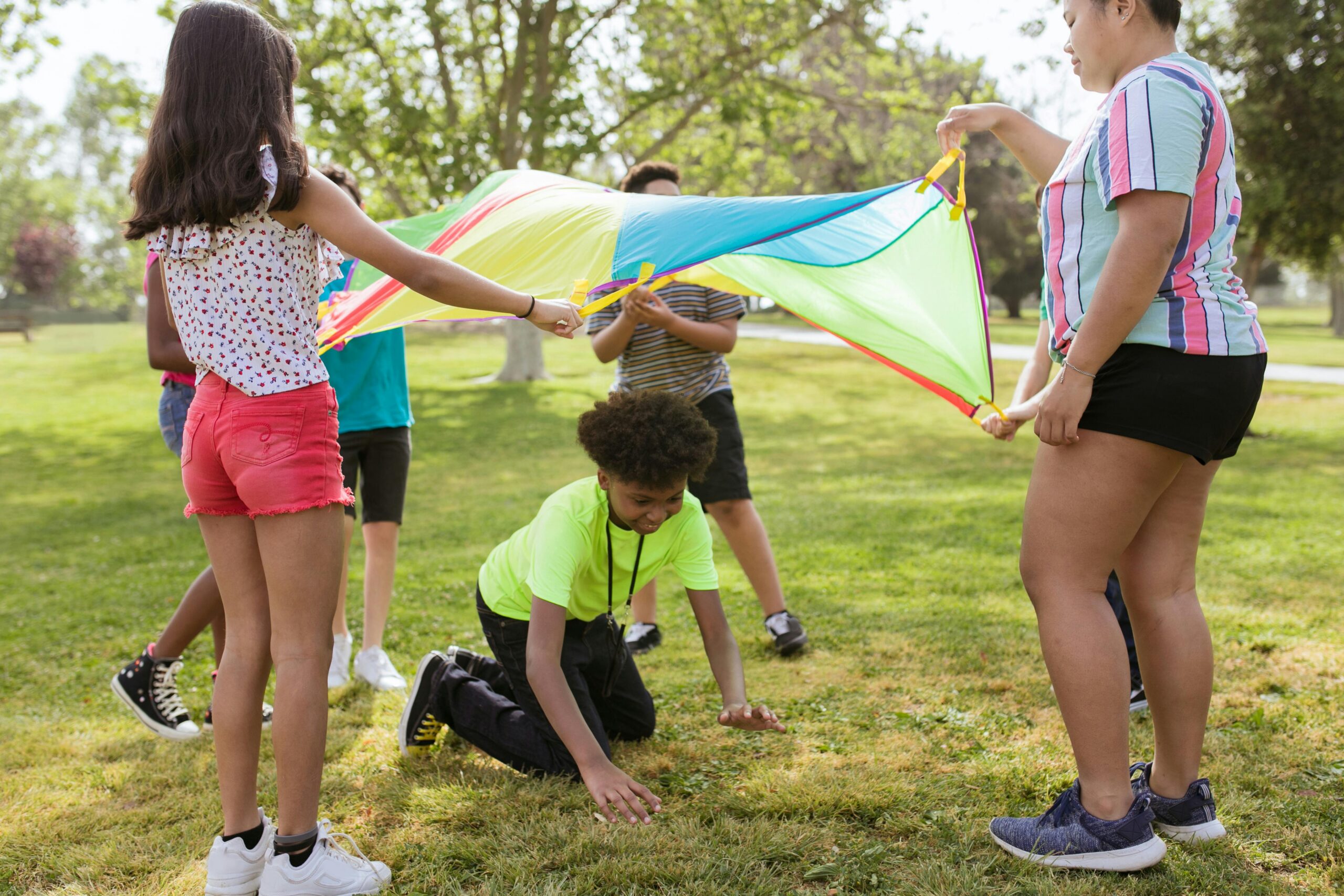 Group of kids playing outside under a parachute
